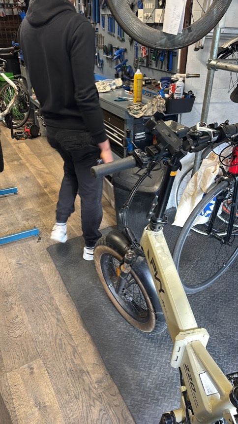 A mechanic rolling an e-bike through the workshop