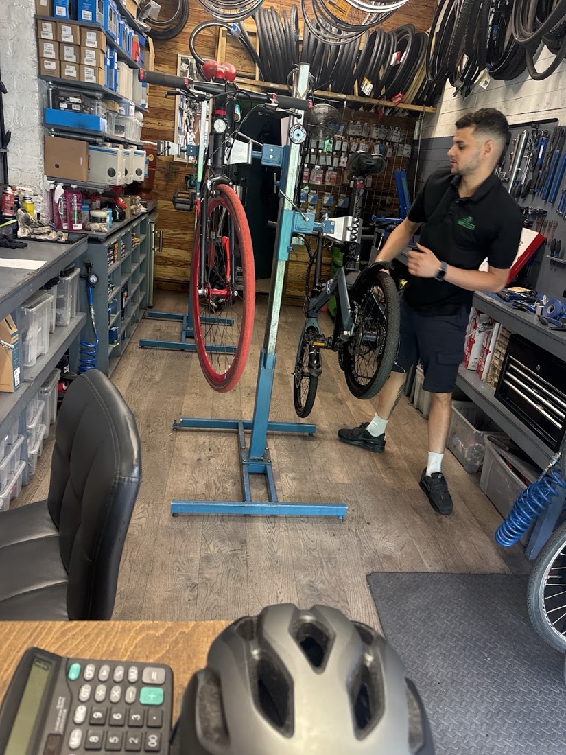 A Way Cycles mechanic servicing a bike on a workshop stand